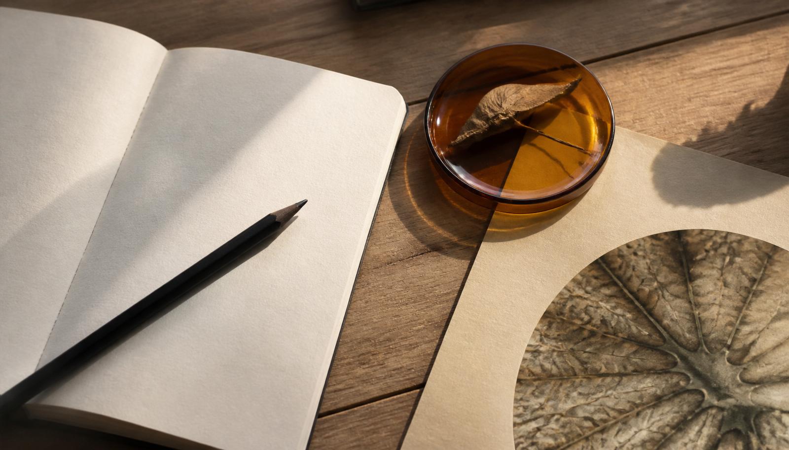 A research notebook and amber glass objects arranged in soft window light.